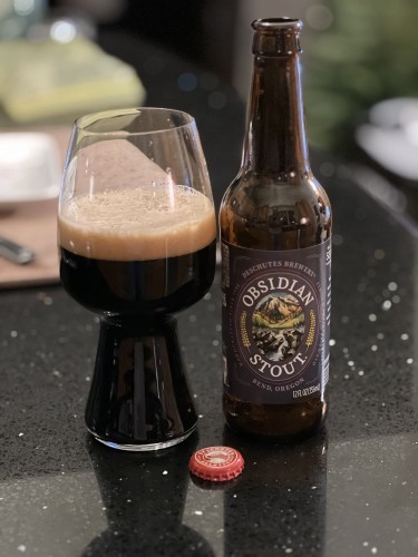 A bottle of Deschuetes Brewing Obsidian stout with a special stout glass to the left