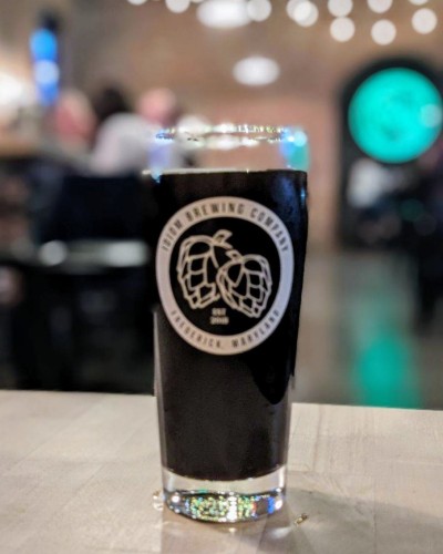 Black beer in a glass with a white Idiom logo.