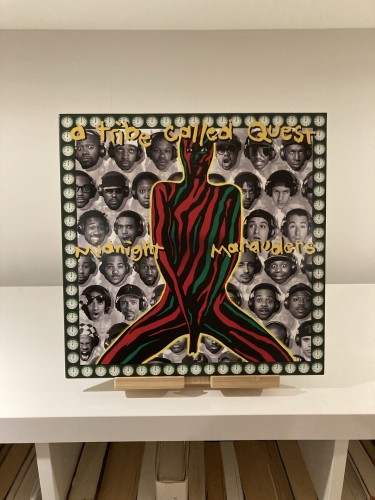 vinyl record cover of Tribe Called Quest’s Midnight Marauders, featuring portrait images of rappers, and a central black figure with artistic, colorful red and green lines and a border with clocks showing midnight.
