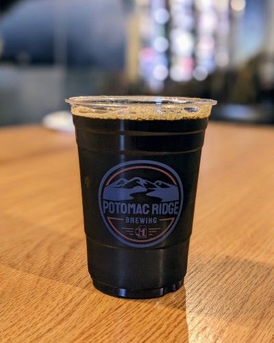 Black beer in a plastic cup. Potomac Ridge logo on the cup.